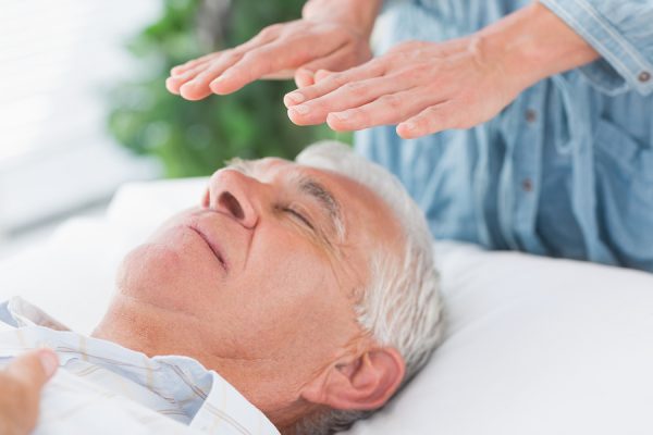 Man receiving Healing Touch therapy from a Mind-Body Energy Medicine specialist.