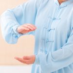 Woman practicing Qigong wearing professional, original Chinese clothes, at home