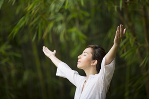 Woman practicing QiGong in a garden as part of a healthy lifestyle and relaxation therapy.