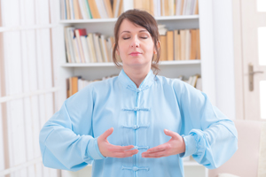 Woman practicing Qigong wearing professional, original Chinese clothes, at home