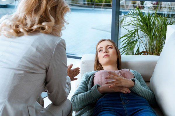 Young woman lying down and talking with her Mind-Body medicine specialist during a guided Imagery session